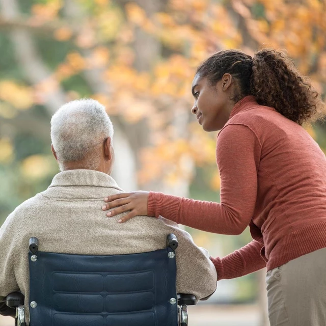 Daughter speaking to father in wheelchair