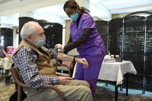 Nurse administering vaccine to senior man