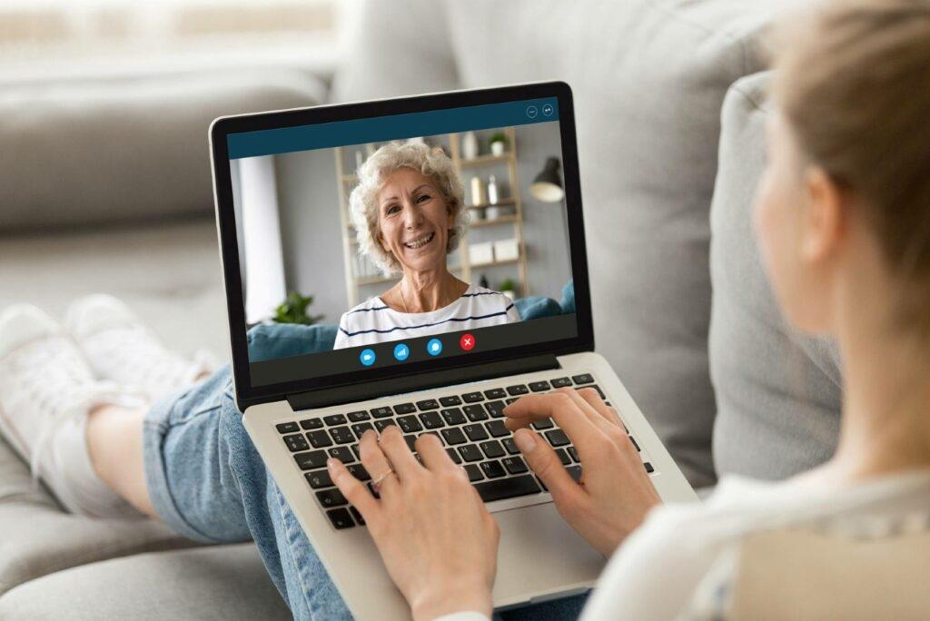 A young woman chats with her grandmother on a video call on a laptop