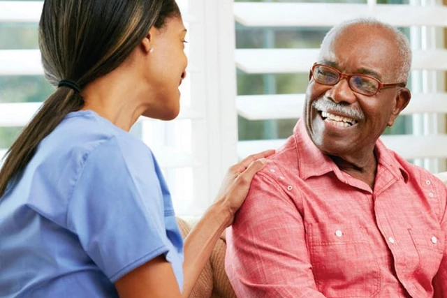 A healthcare professional places her hand on the shoulder of a senior man