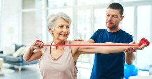 A therapist helps a senior woman go through physical therapy exercises