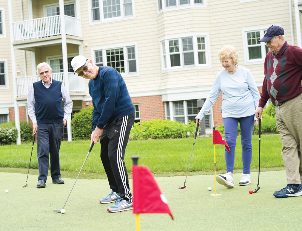4 residents practice putting on putting green located at Meadow Ridge