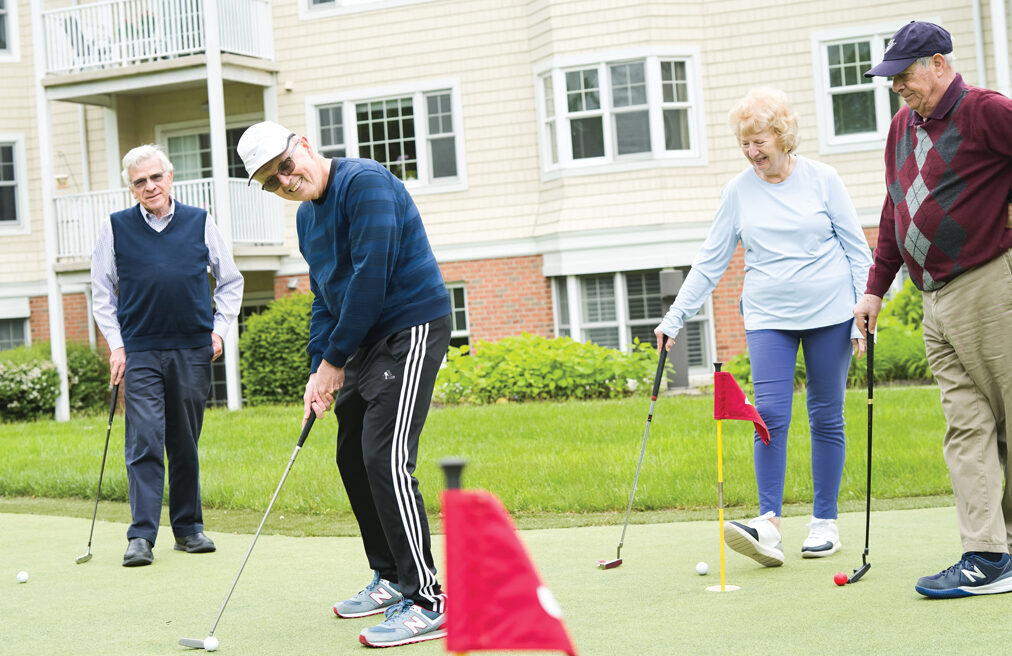4 residents practice putting on putting green located at Meadow Ridge