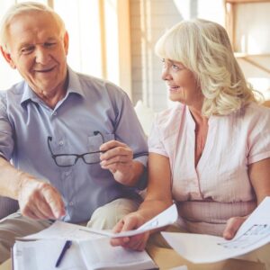 Elderly couple sitting and smiling over papers