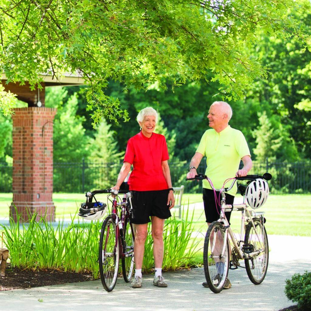 A senior man and a senior woman walking their bikes out to the road