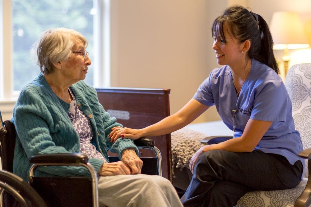 A senior woman in a wheelchair talking with a staff member