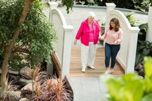 Elderly woman and younger woman walking outside on patio