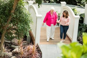 Elderly woman and younger woman walking outside on patio