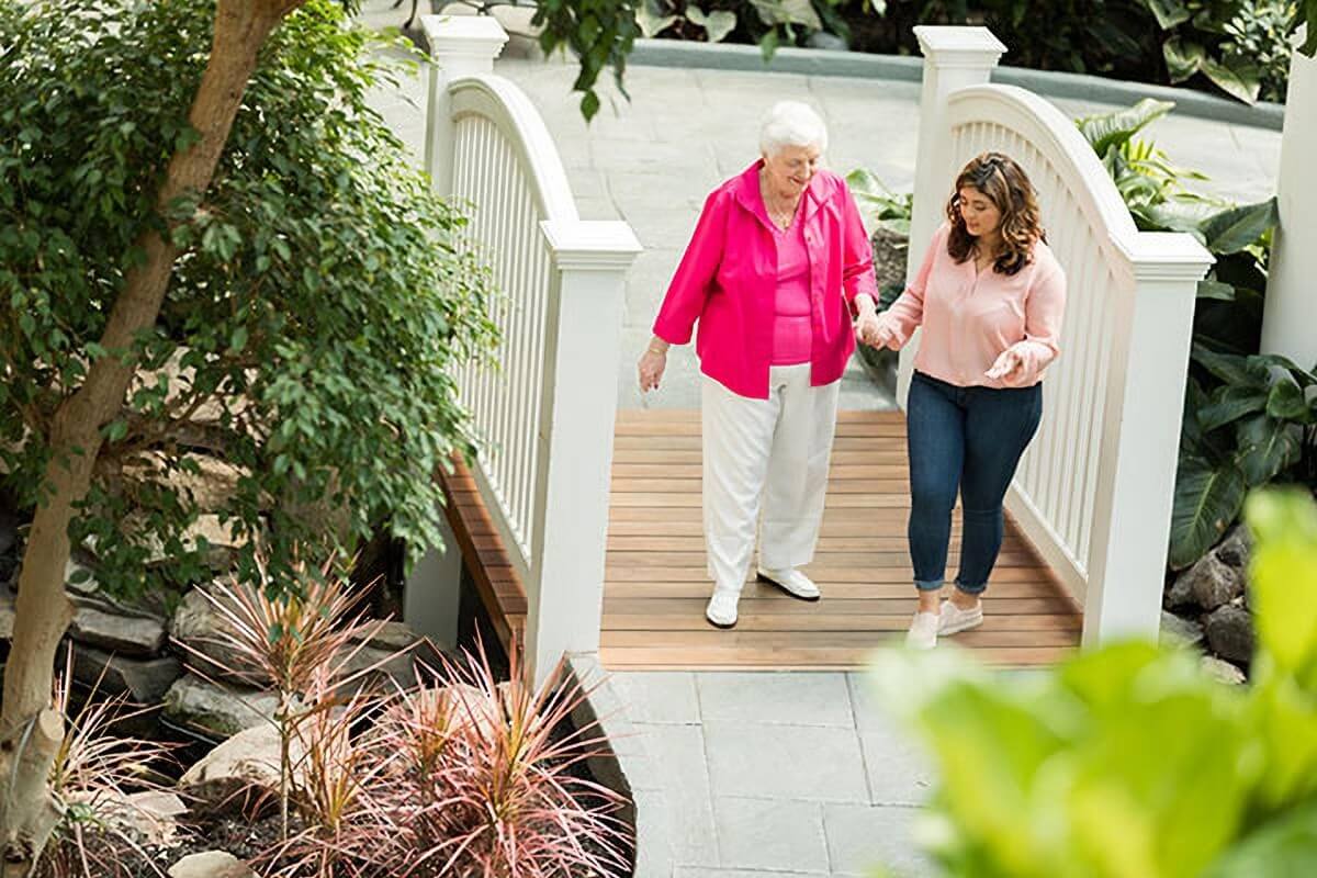 Elderly woman and younger woman walking outside on patio