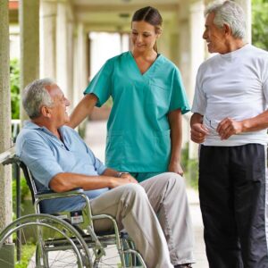 A senior man in a wheelchair talks with a senior living staff member