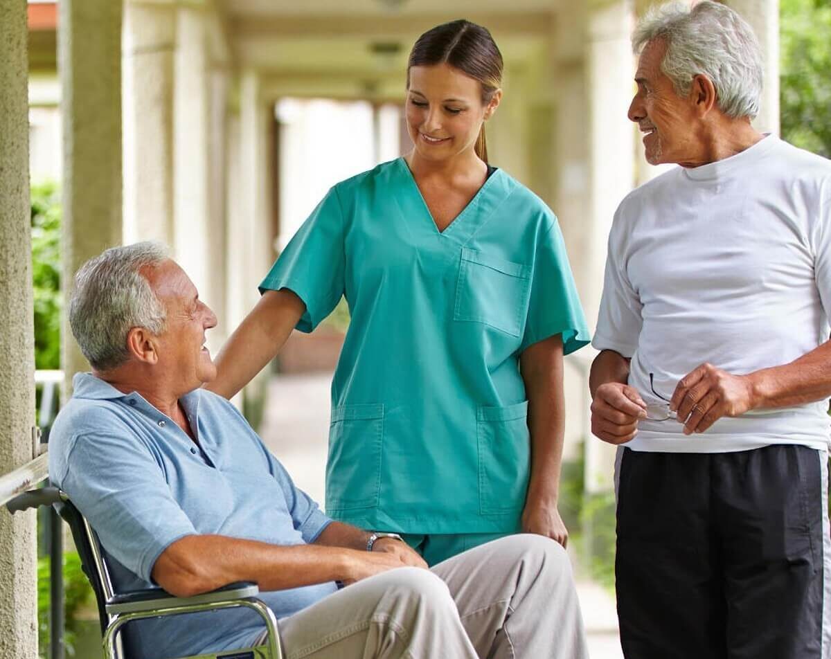 A senior man in a wheelchair talks with a senior living staff member