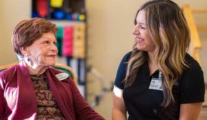 A senior living health care staff talks with an elderly woman
