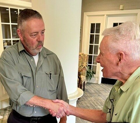 Patrick Boelens shakes hands with a Meadow Ridge resident holding a small plate of fruit during the Mix and Mingle social.